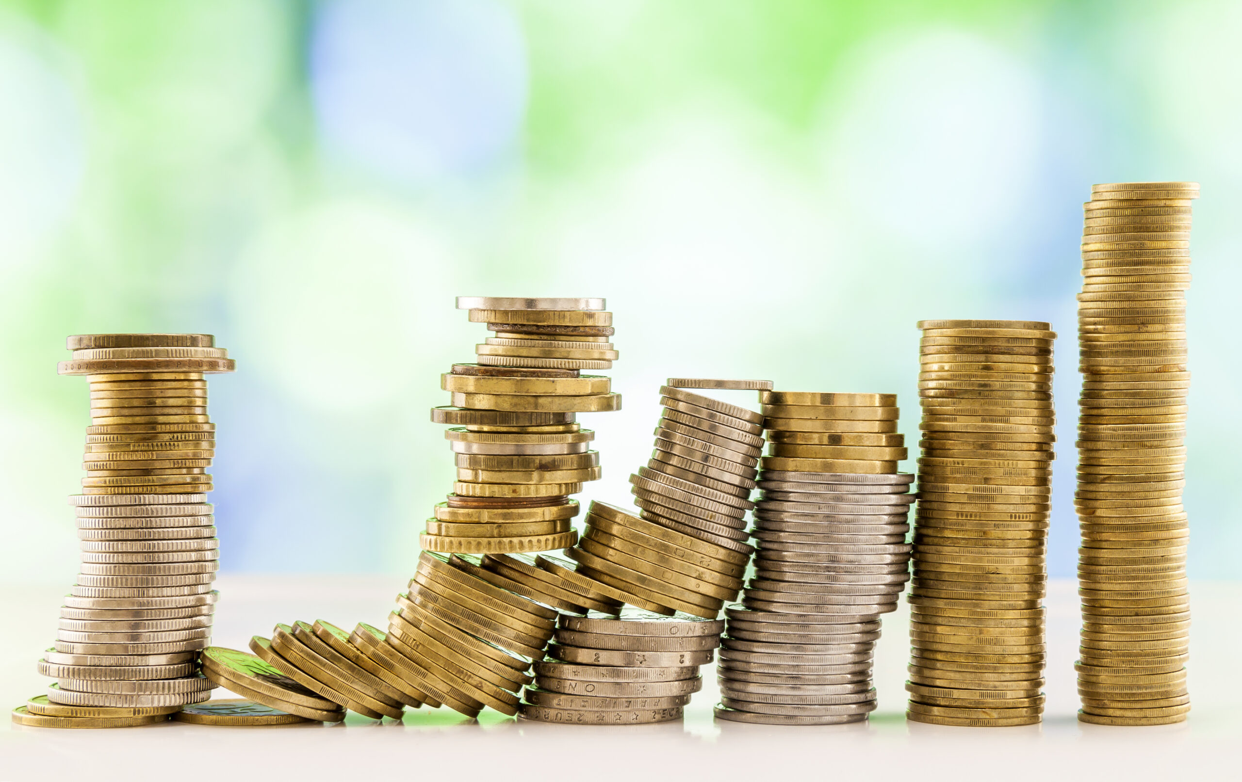 Growing coins stacks with green and blue sparkling bokeh background. Financial growth, saving money, business finance wealth and success concept.